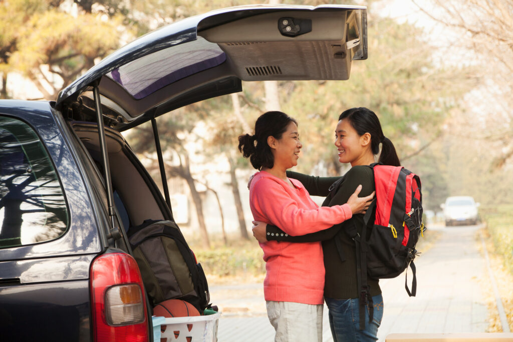 University student hugging her mom goodbye next to her car.