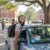 a university student standing next to her new car smiling